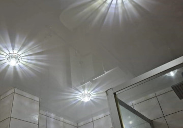 Lichtspiel im kleinen Badezimmer: Hochglänzende weiße Spanndecke mit funkelnden Einbaustrahlern aus Kristallglas